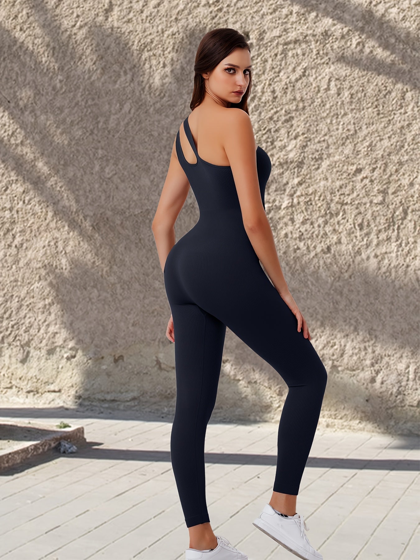 Asymmetrical shoulder ribbed yoga bodysuit for women with full-length leggings and contour design.

